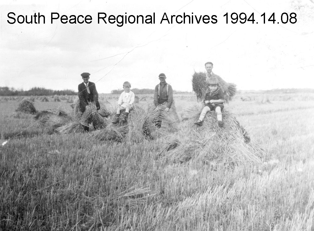 Nels Carlson, Howard Gummer, Ed Gummer, Mr. Grover (teacher at Chatham) and Jean Gummer taking a break in a field of stooked grain.c.1926