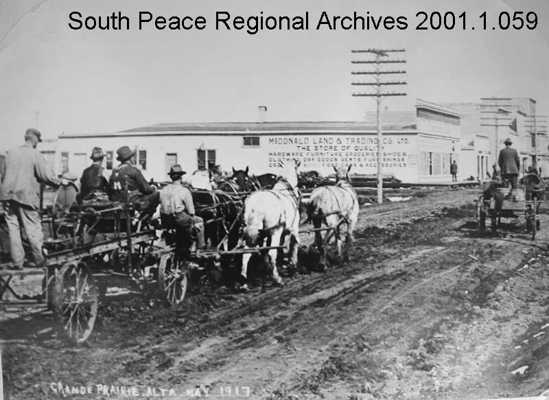 Eight horses pull a grader down Richmond Avenue in front of McDonald Land & Trading Company. This was the first piece of road equipment purchased by the Village of Grande Prairie Public Works Department. (1917)